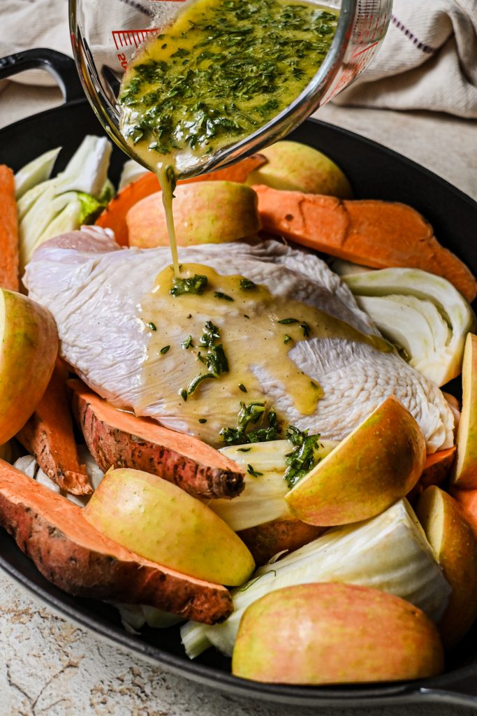 Pouring the maple marinade over the top of the turkey breast and vegetables.