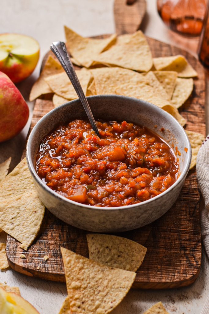 Southern apple salsa served in a bowls on a wooden board with tortilla chips around it.