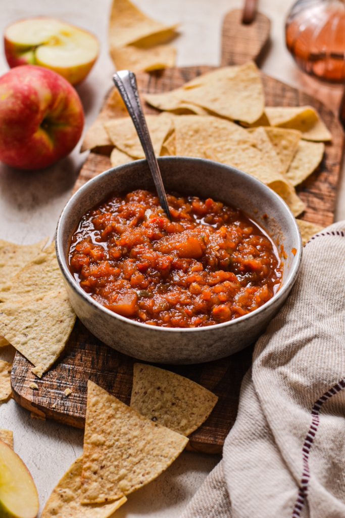 Southern apple salsa served in a bowl with tortilla chips scattered around it.