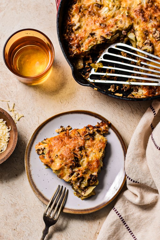 Ground beef and cabbage gratin served on a plate with the skillet next to it.