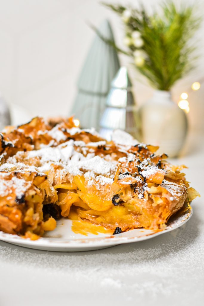 Flaky apple tart on a plate with a slice missing.