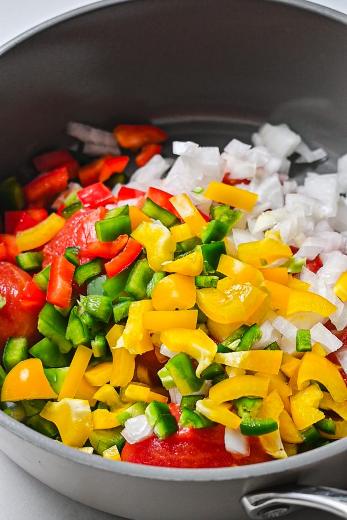 Freshly chopped vegetables being added to a saucepan to cook.