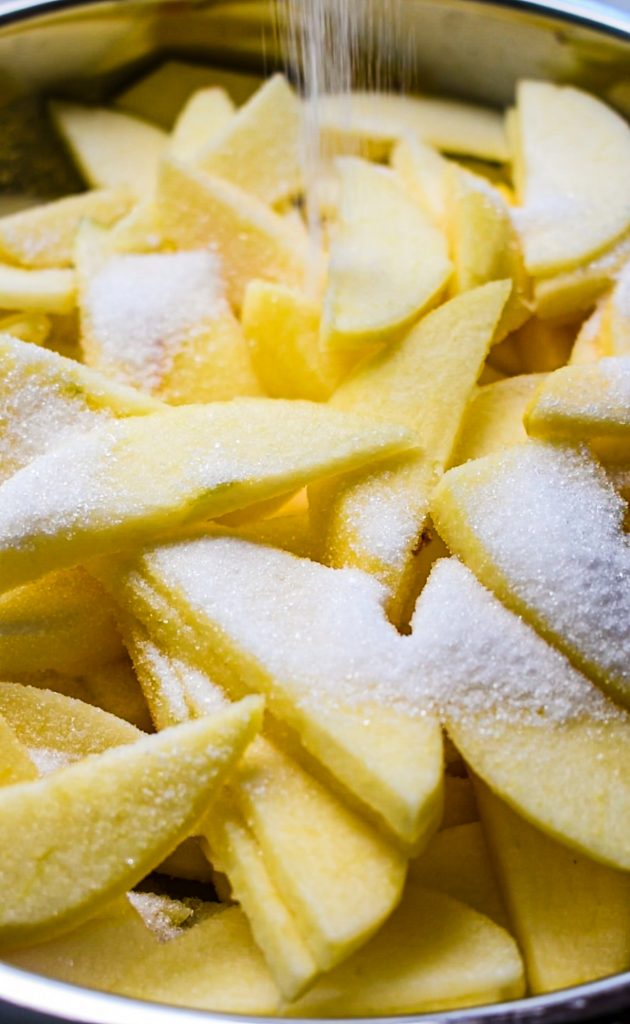 Sliced apples and sugar in a mixing bowl.