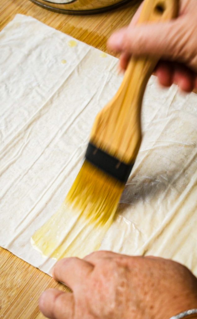 Brushing the phyllo dough with melted butter.