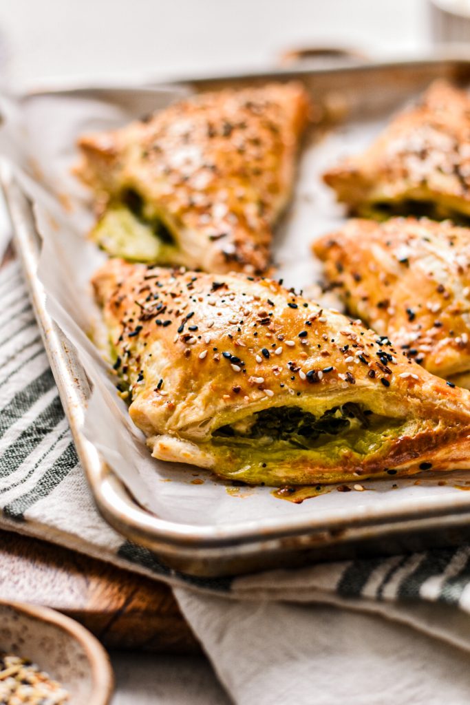 Side view of the spanakopita turnovers on a sheet pan.