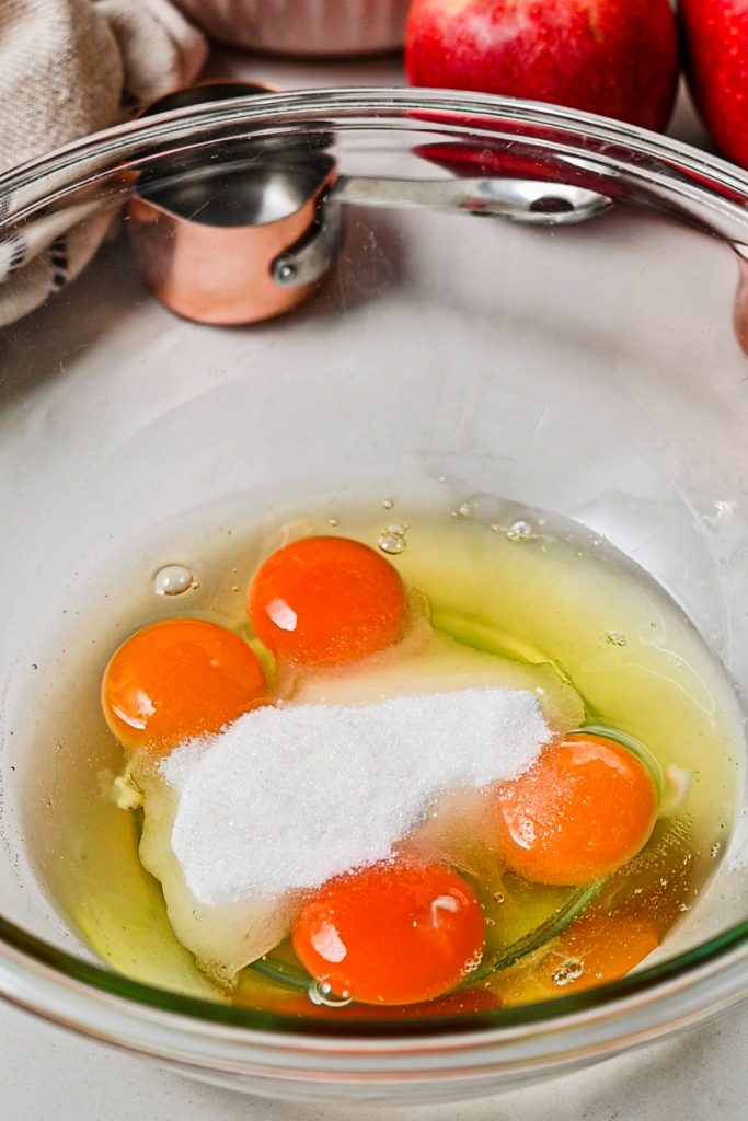 Eggs and sugar in a glass mixing bowl.