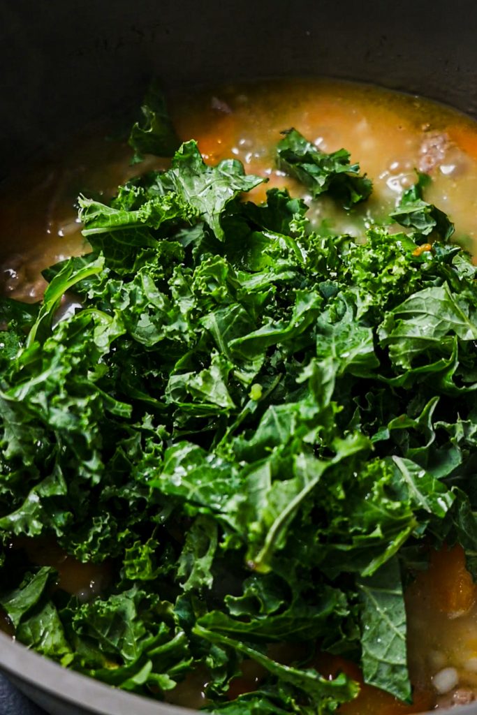 Chopped kale added to the pot of soup.