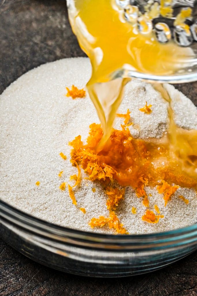 Pouring the orange juice into a mixing bowl with cornmeal mix, sugar, and orange zest in it.