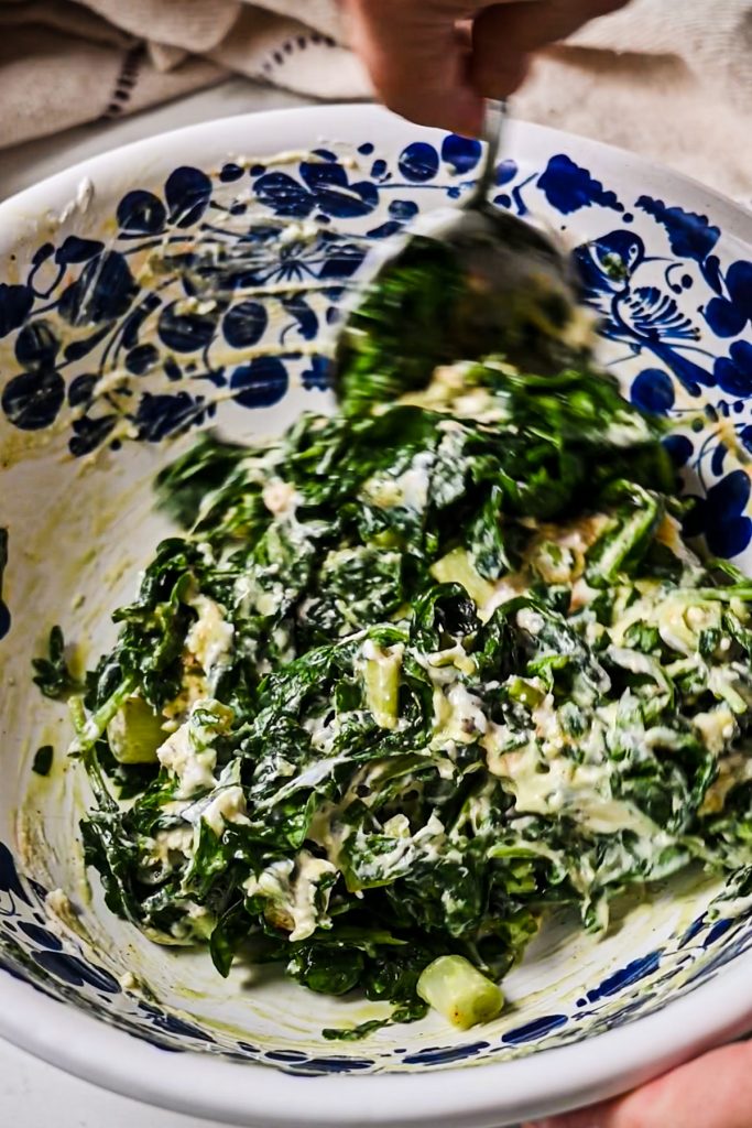 Mixing the spanakopita filling in a mixing bowl.