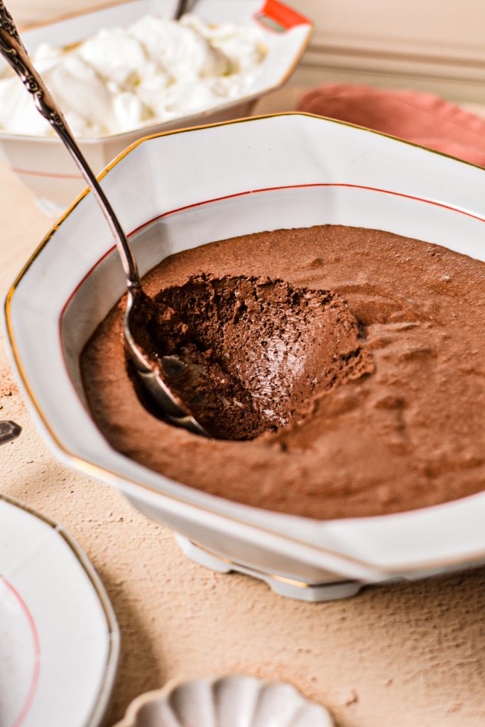 Chocolate mousse in a serving bowl with a spoon scooping some out.