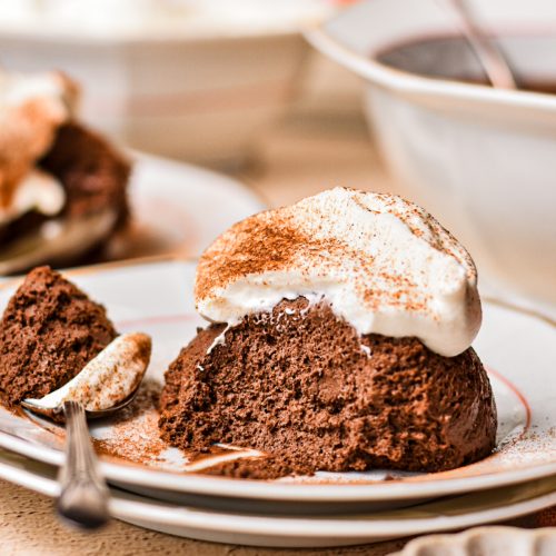 Side view of a plate served with chocolate mousse and whipped cream with a spoon on the side.