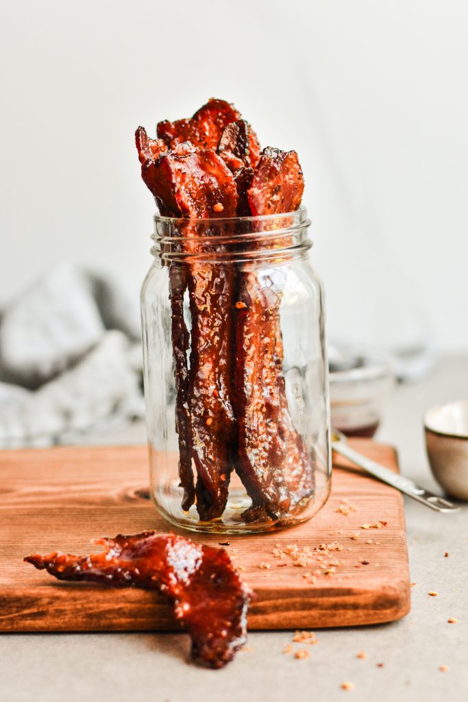 Million dollar bacon pieces placed into a jar with one slice on the side.