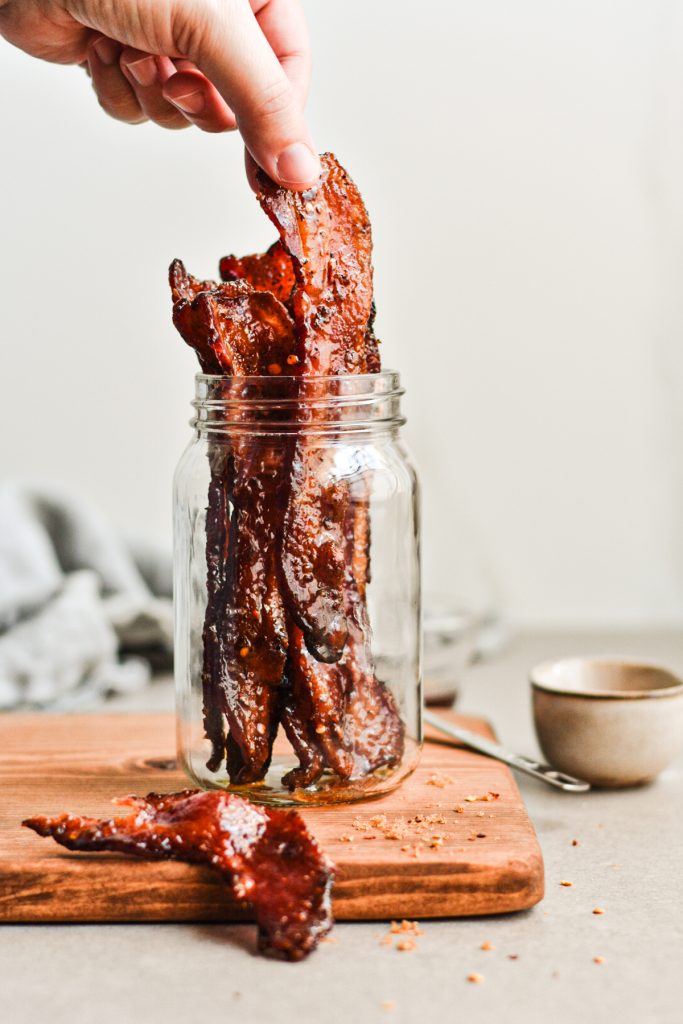 Hand taking a piece of the million dollar bacon from the jar.