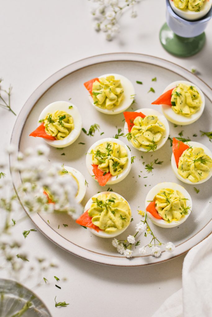 Deviled eggs served on a plate with smoked salmon and fresh dill as garnish.