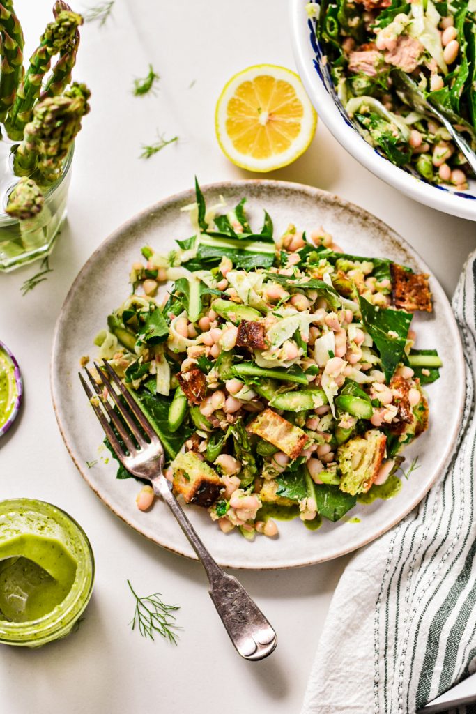 Overhead shot of raw asparagus white bean tuna salad served on a white speckled plate.