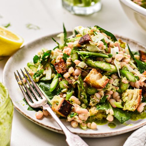Asparagus white bean tuna salad piled on a plate with a fork.