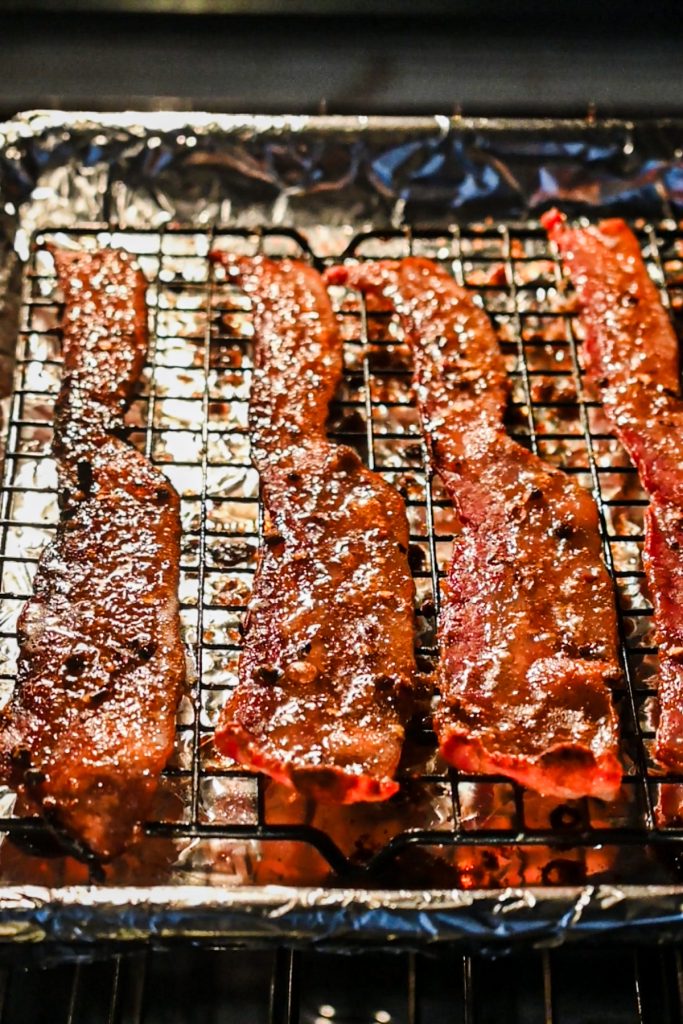 Million dollar bacon on a baking sheet lined with a wire rack in the oven.