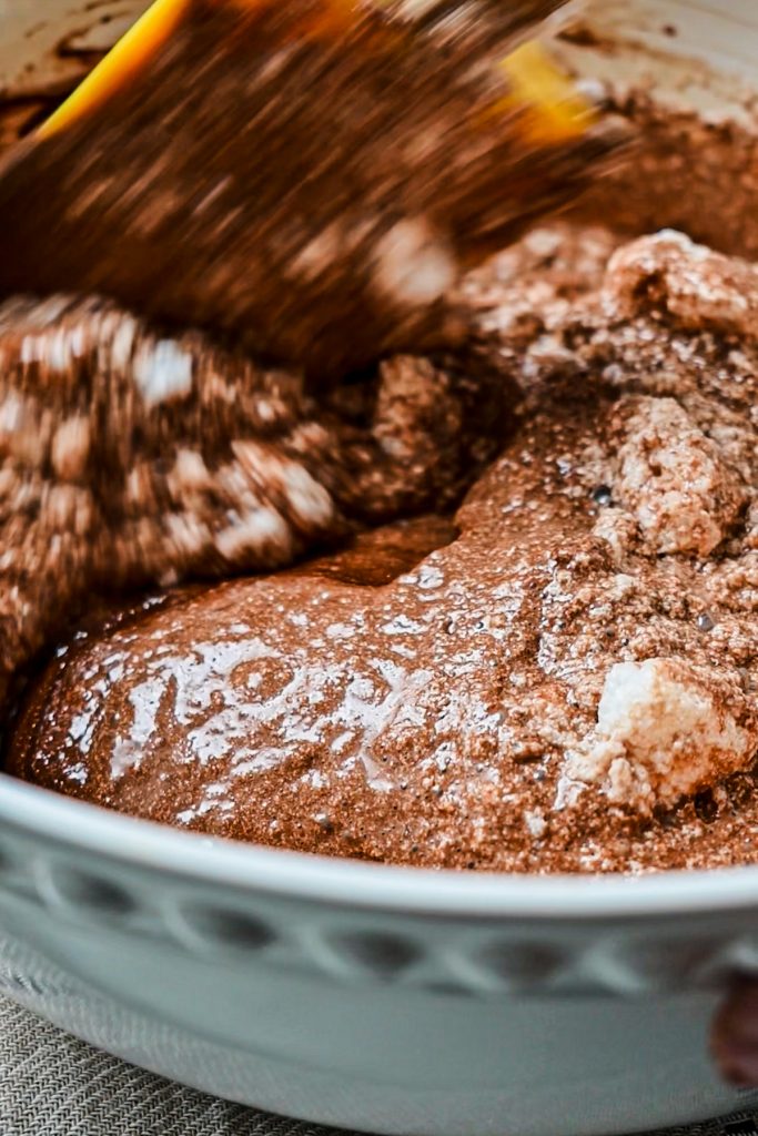 Folding in the first portion of egg whites into the chocolate egg yolk mixture.