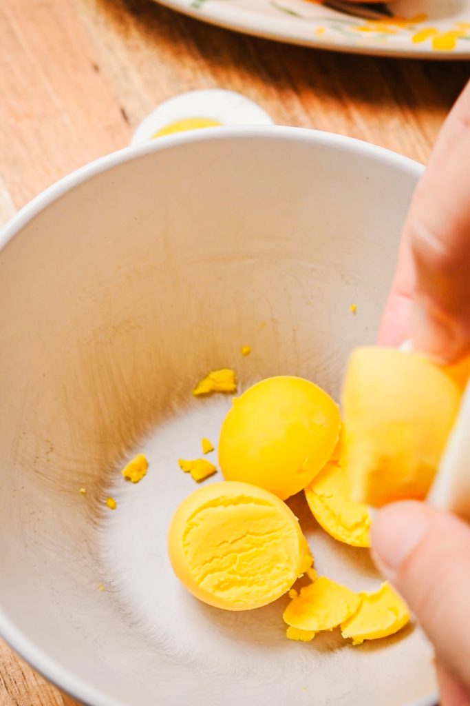 Separating the hard boiled egg yolks from the egg whites in a small bowl.