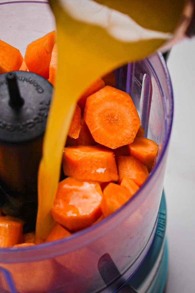 Carrots and orange juice in a food processor before being blended.