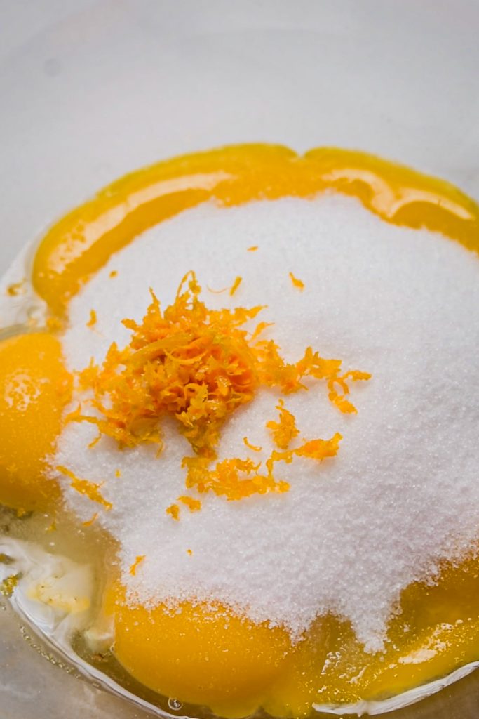 Orange zest added to the bowl with egg yolks and sugar.