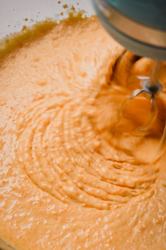 Using an electric mixer to combine the carrot mixture and the cake batter.