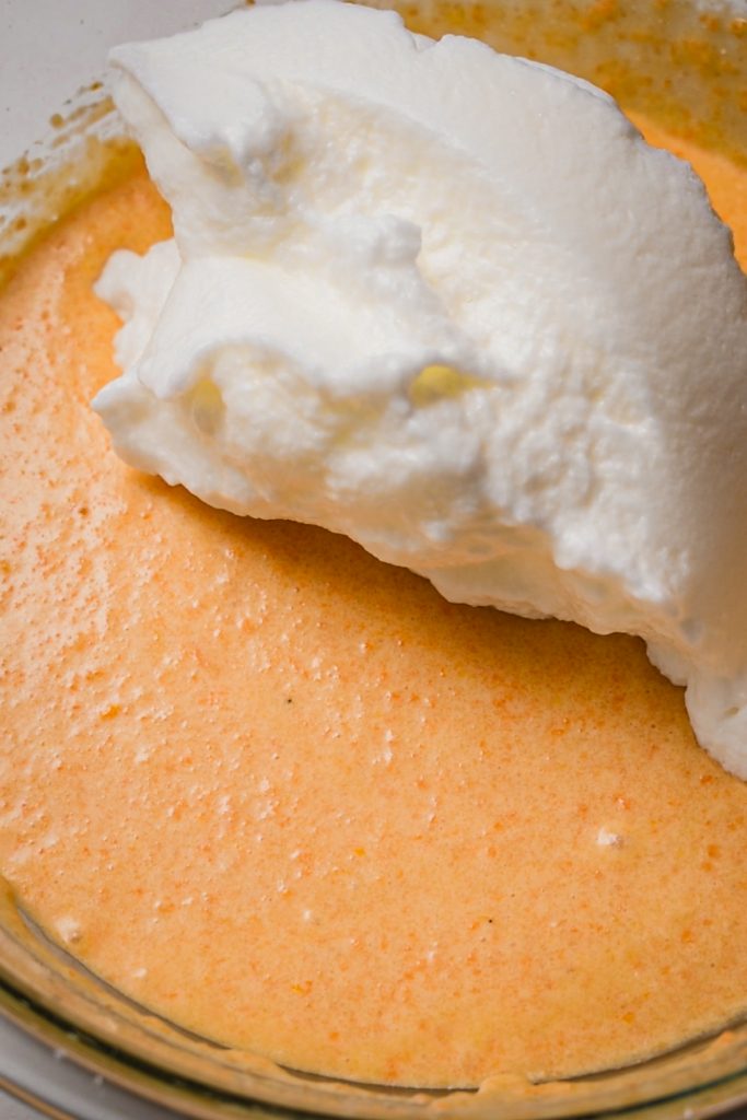 Fluffy egg white being added to the carrot cake batter.