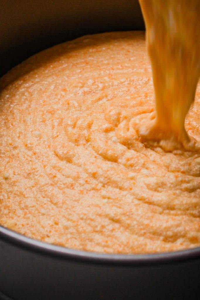 Pouring the prepared carrot orange torta caprese batter into a cake pan.