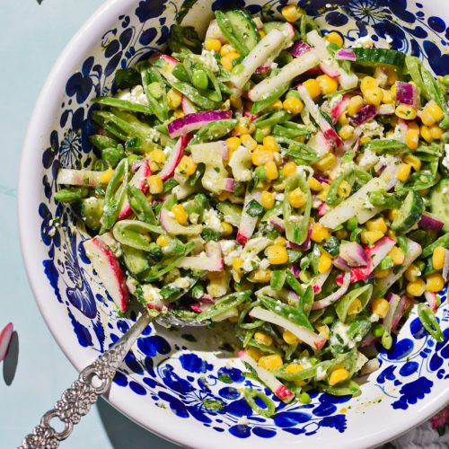 Overhead shot of a sugar snap pea salad with feta in a serving bowl.