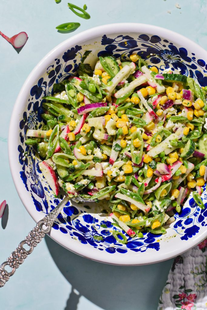 Overhead shot of a sugar snap pea salad with feta in a serving bowl.