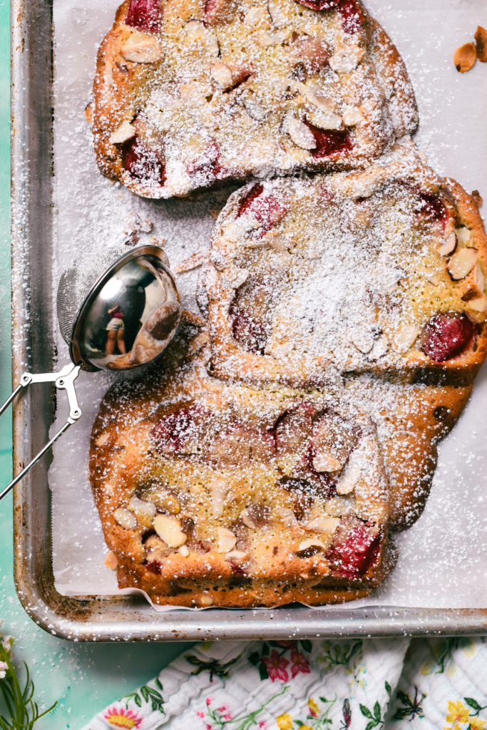 Three slices of bread topped with compote and almond cream and garnished with powdered sugar.
