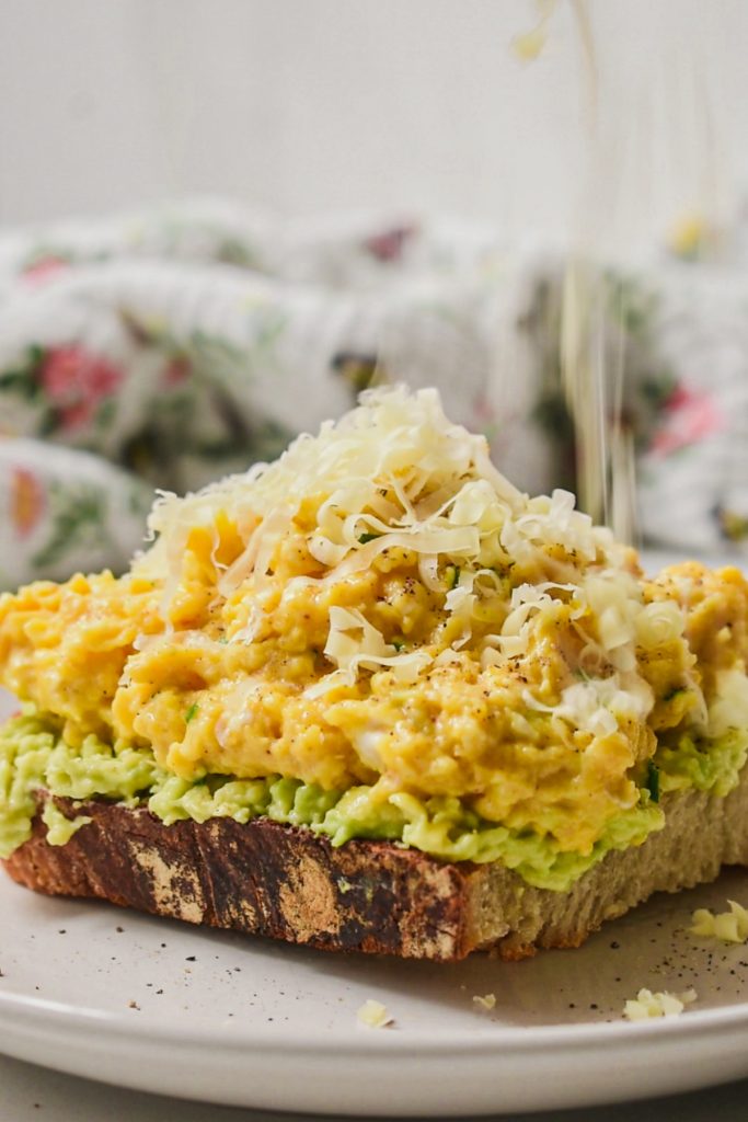 Creamy eggs with cottage cheese on avocado toast on a plate.