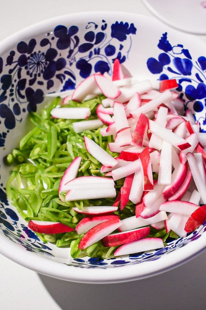 Sliced radishes and snap peas in a bowl.