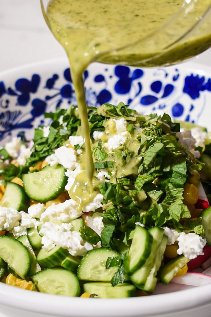 Pouring the mint dressing over the top of the sugar snap pea salad before tossing it.