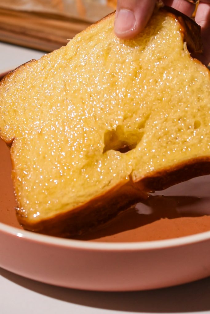 Dipping a slice of challah bread in simple syrup.