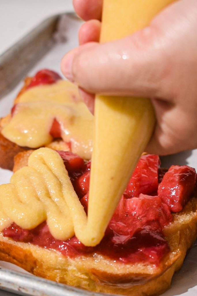 Piping the almond cream on top of the fruit compote on the bread.