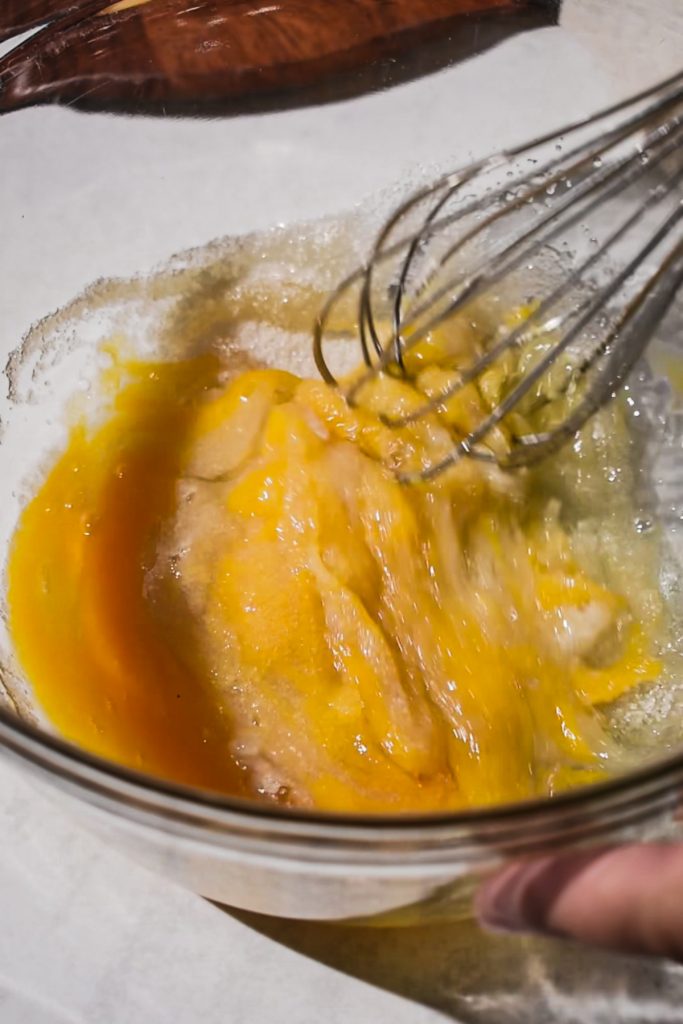 Whisking together the eggs and sugar in a mixing bowl.