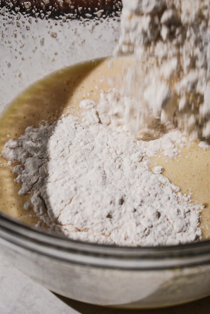 Adding the dry ingredients to the peach cake batter.