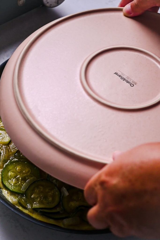 Placing a plate over the top of the tortilla to flip it.