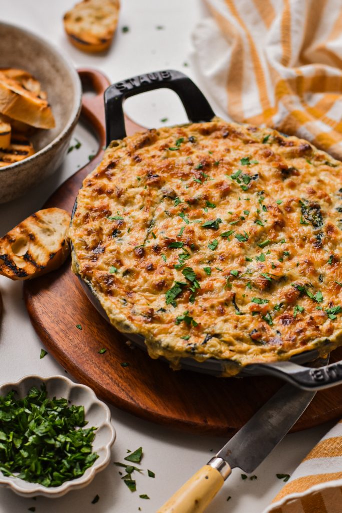 Cajun crab spinach artichoke dip in a cast iron skillet topped with melted cheese.
