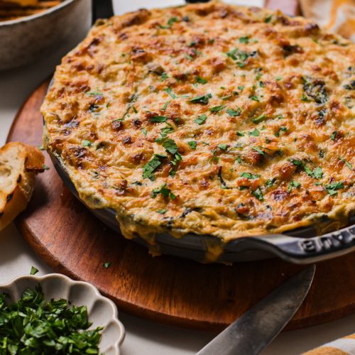 Cajun crab spinach artichoke dip served in a cast iron skillet wit melted cheese on top.