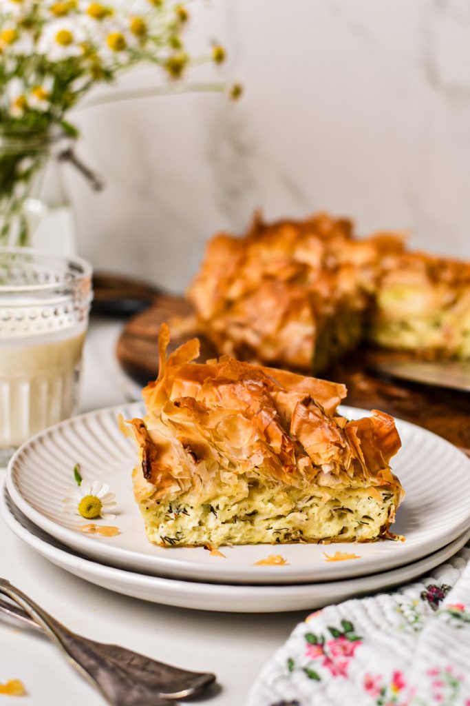 Side view of a slice of farmer cheese phyllo pie with a ruffle of phyllo on top.