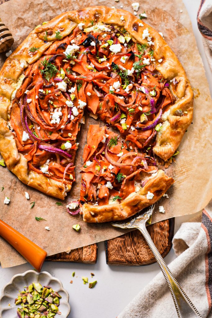 Overhead shot of the spicy carrot galette on a piece of parchment on a wooden board.