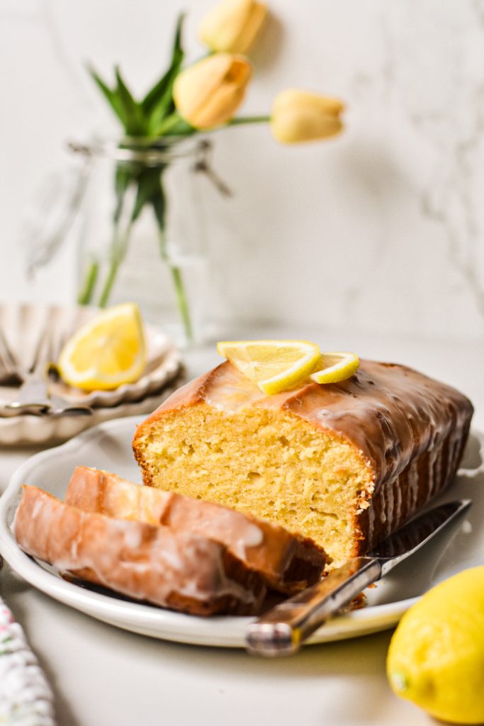 Lemon loaf cake on a serving plate with two slices off the end.