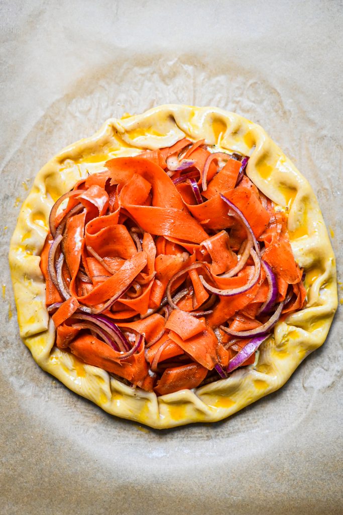 Edges of the pie crust folded in towards the filling to create a galette shape, before baking.