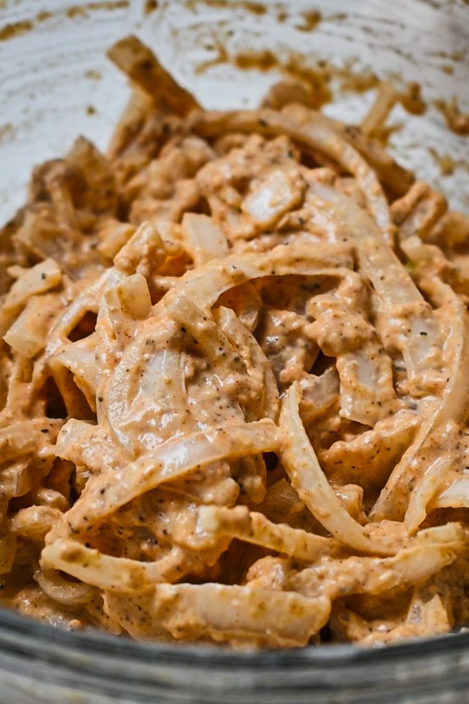 Onions coated in the flour and spice mixture being being fried.