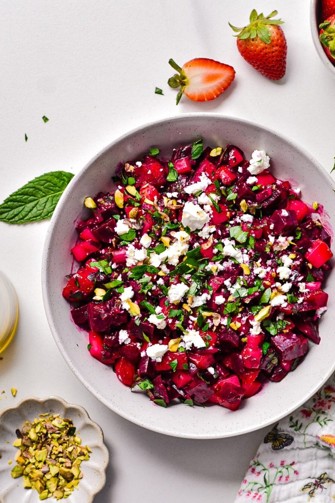 Overhead shot of beet strawberry salad topped with feta and pistachios.