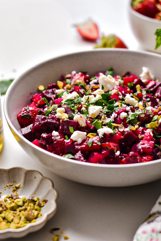 Side view of beet strawberry salad topped with feta and pistachios.
