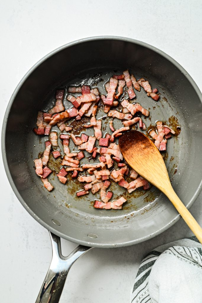 Chopped bacon cooking in a skillet.