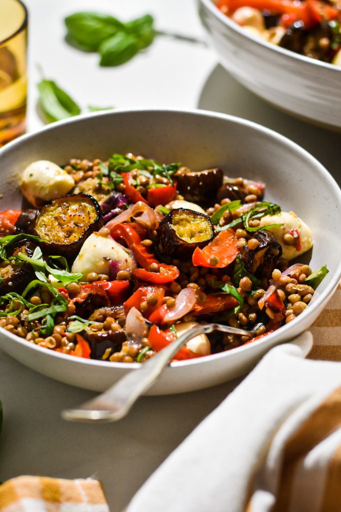 Close up of roasted eggplant lentil salad with a fork in the bowl.